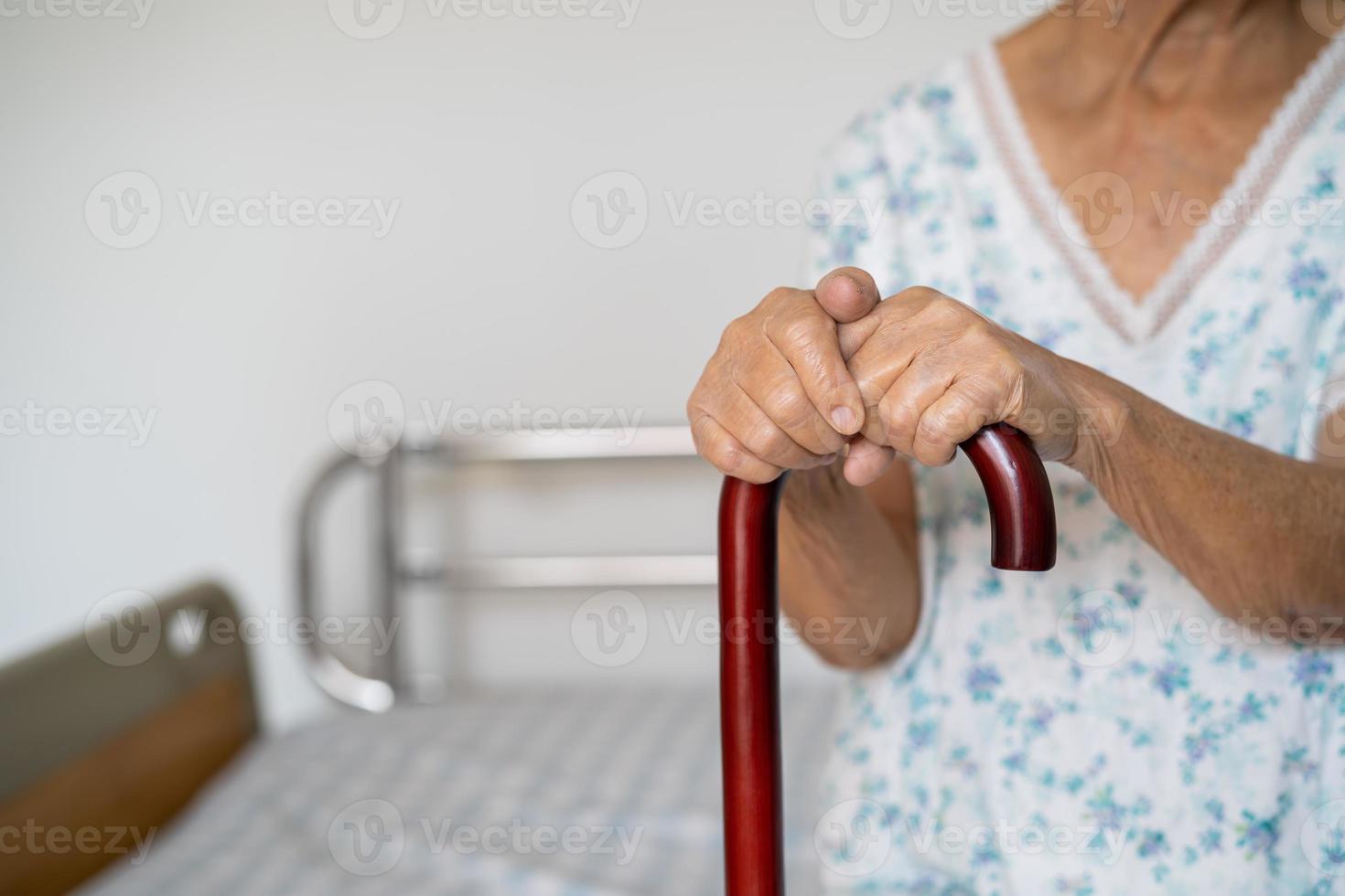 Asian elderly disability woman holding waling stick, wood cane, round handle, walking aid for help to walk. photo