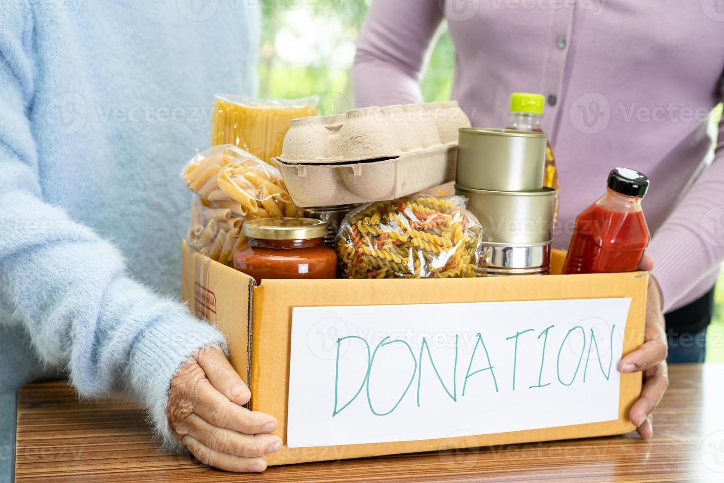 Volunteers putting various dry food in donation box for help people. photo