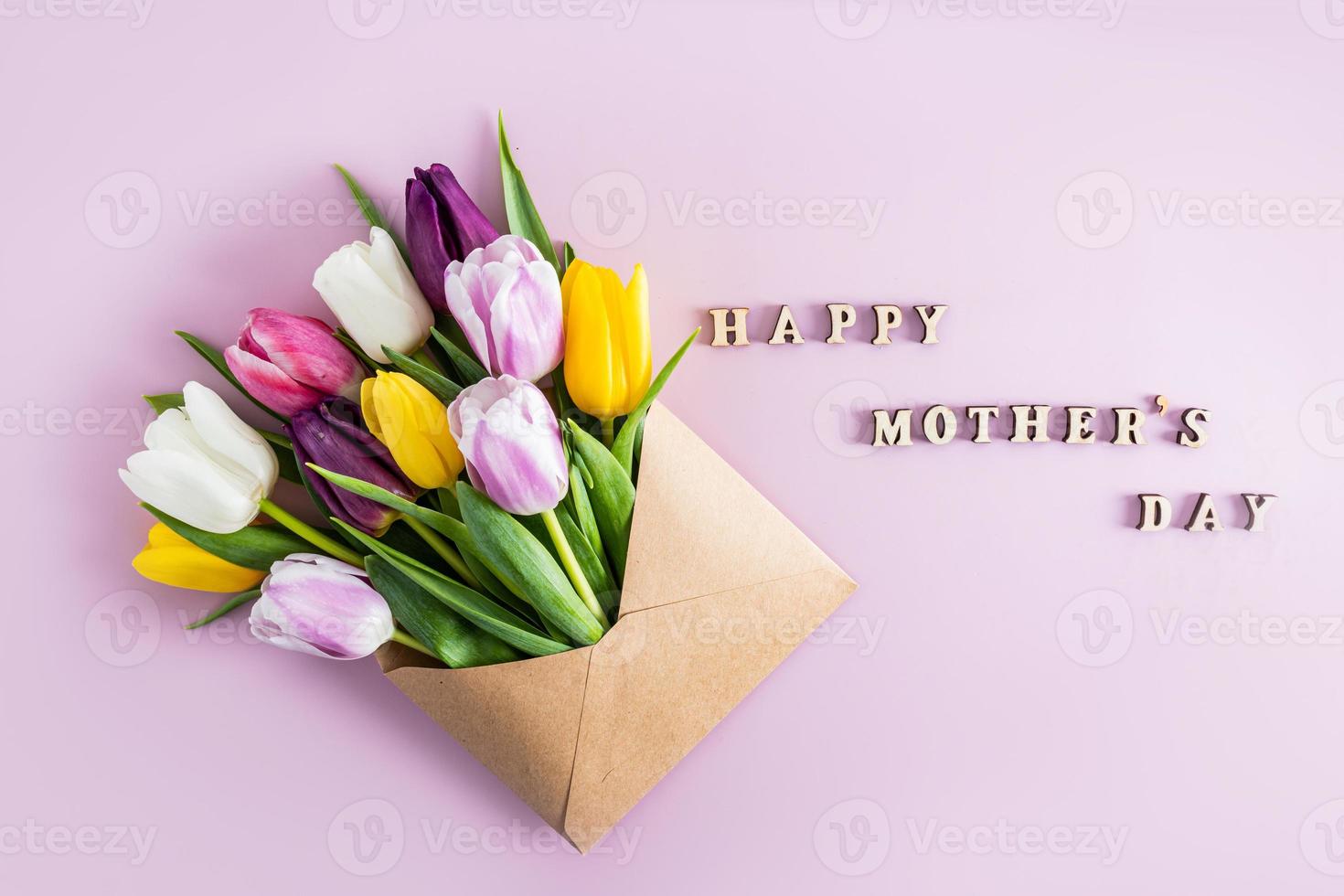 beautiful spring composition for Mother's Day. multi-colored tulips in a craft envelope. top view. flat layout. text wooden letters. photo