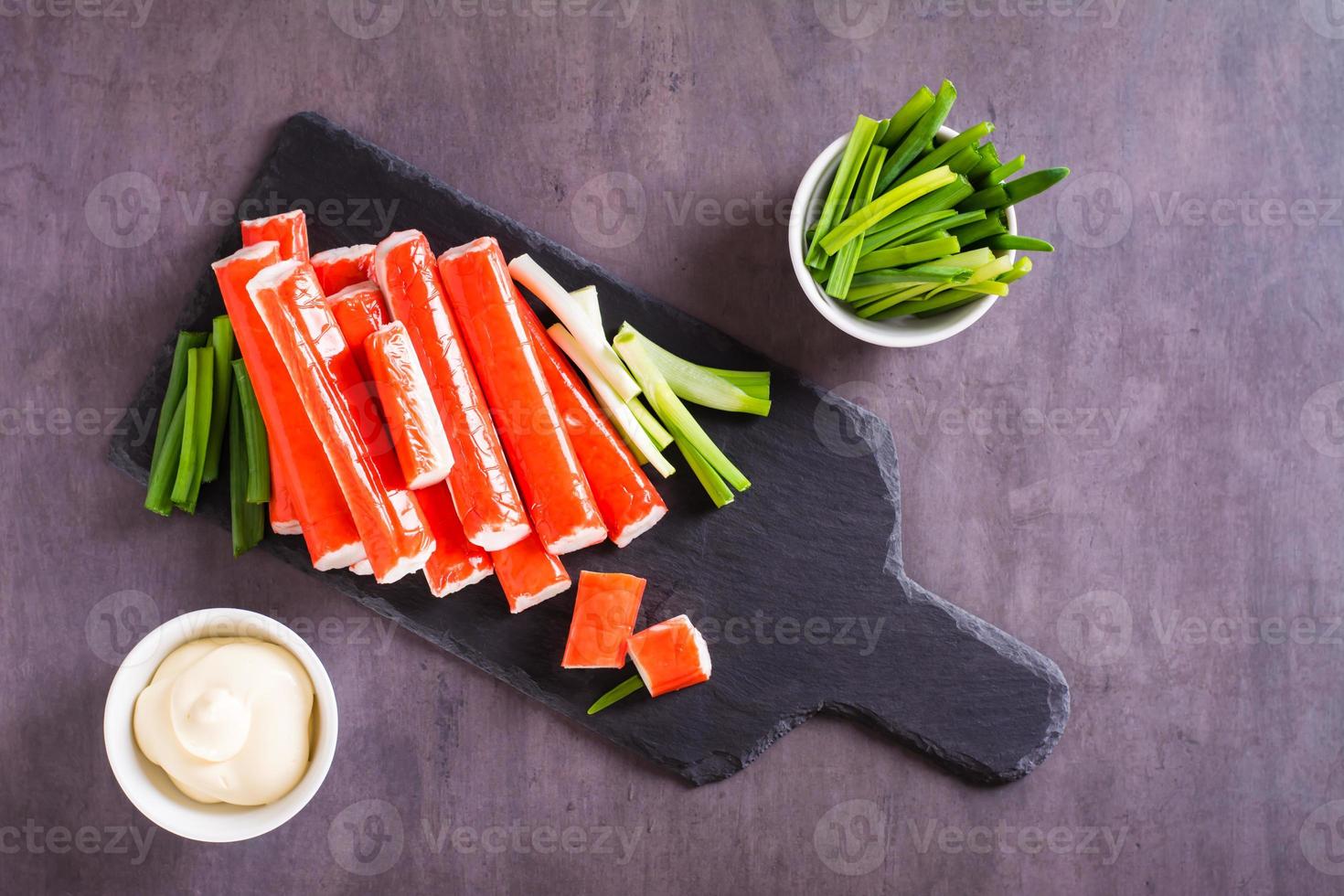 Minced fish crab sticks and green onions on a stone board ready to eat. Top view photo