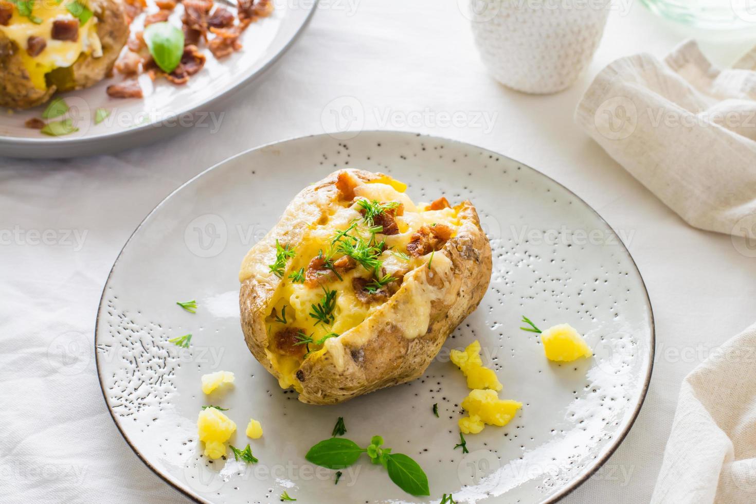 Appetizing twice-baked potatoes in their skins with cheese and bacon crumbs on plates on a wooden table. Flexitarian Diet. Close-up photo