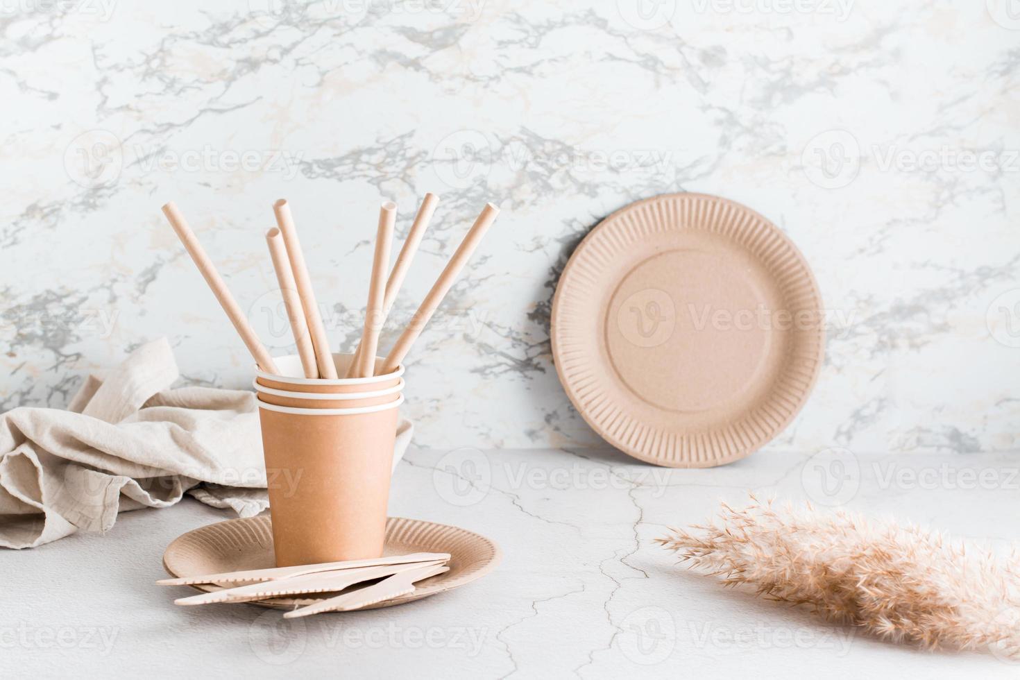 Eco friendly cardboard disposable tableware. Plates, cups, tubules and wooden knives are on the table. photo