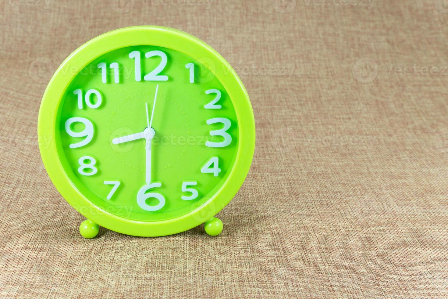 Green alarm clock on brown sackcloth background show half eight o'clock or 8.30 a.m. photo