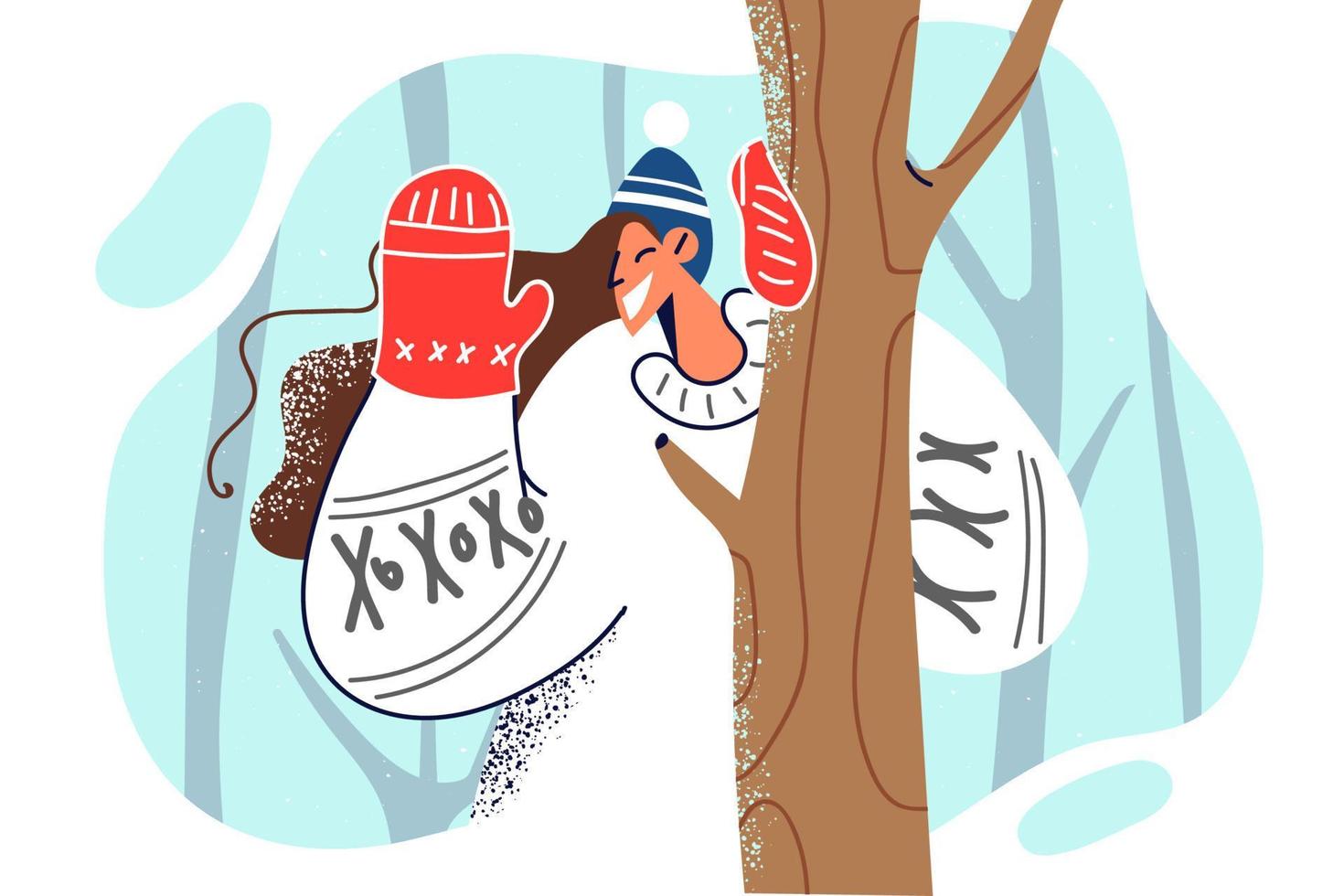 Woman in Scandinavian sweater waves hand standing in forest among trees during winter trip. Girl says hello raising hand with glove enjoying walk in winter park on Christmas weekend vector
