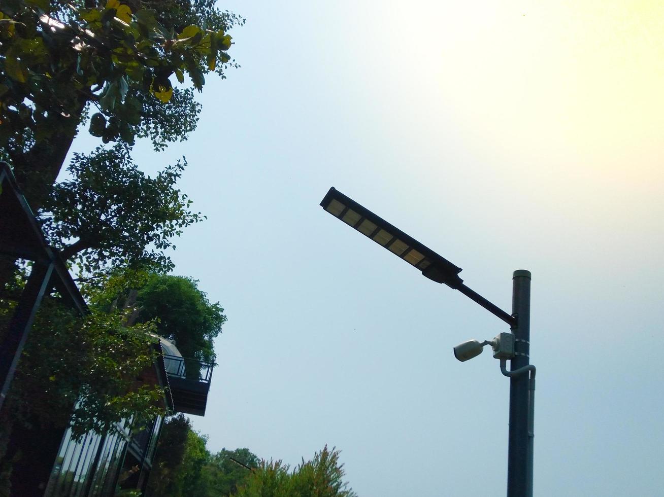 solar energy  On the iron pole next to the fence of the house was a large tree.  use of clean energy photo
