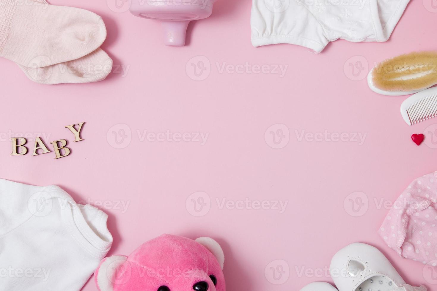 Flat lay composition with baby accessories and toys on a colored pink background. Top view frame from baby accessories. Copy space photo