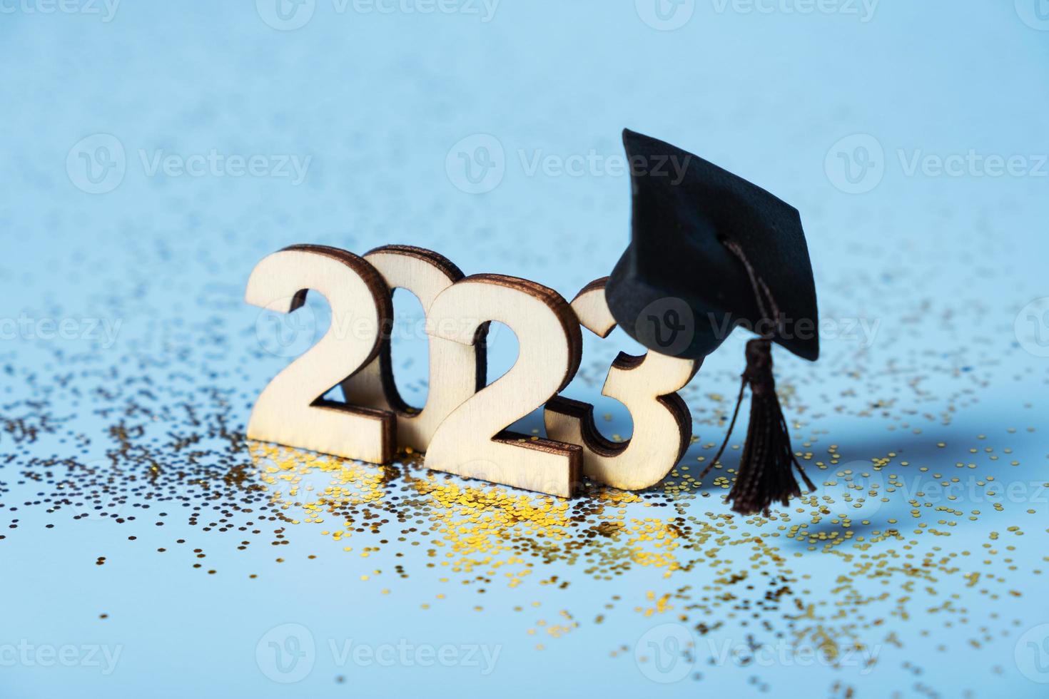 Class of 2023 concept. Wooden number 2023 with graduated cap on colored background photo