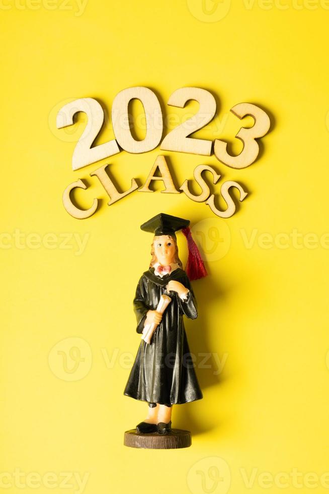 Class of 2023 concept. Wooden number 2023 with graduate statuette on color background photo