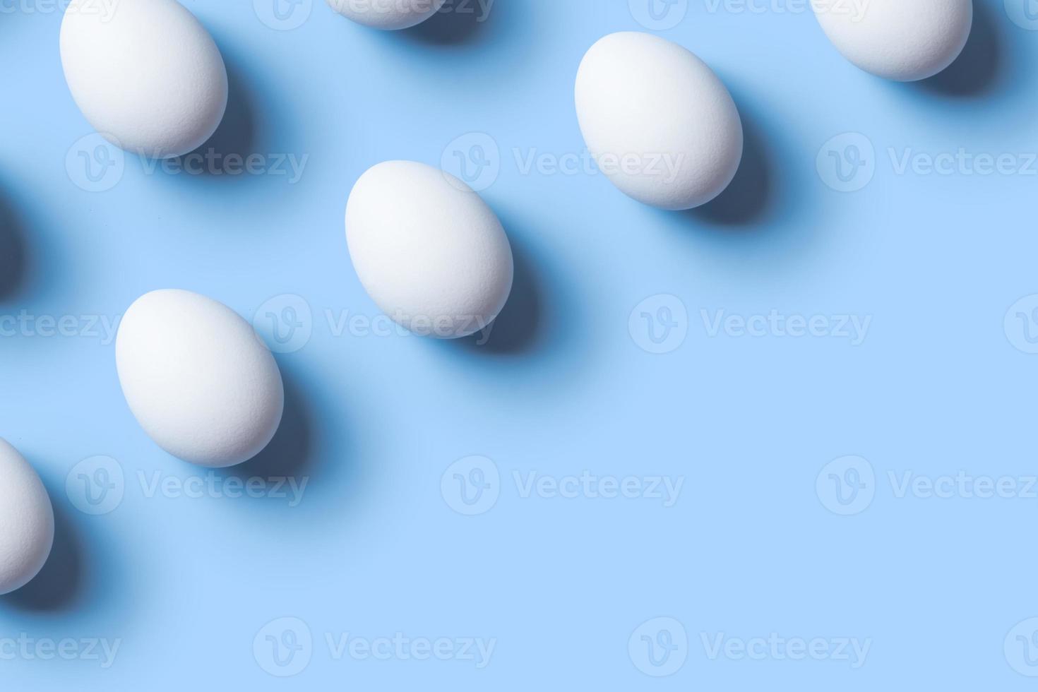 Creative composition with pattern from white eggs on blue background. Copy space photo