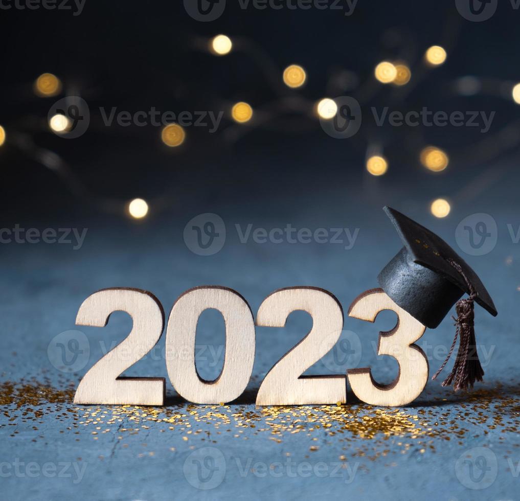 Class of 2023 concept. Wooden number 2023 with graduate cap on dark background with bokeh photo
