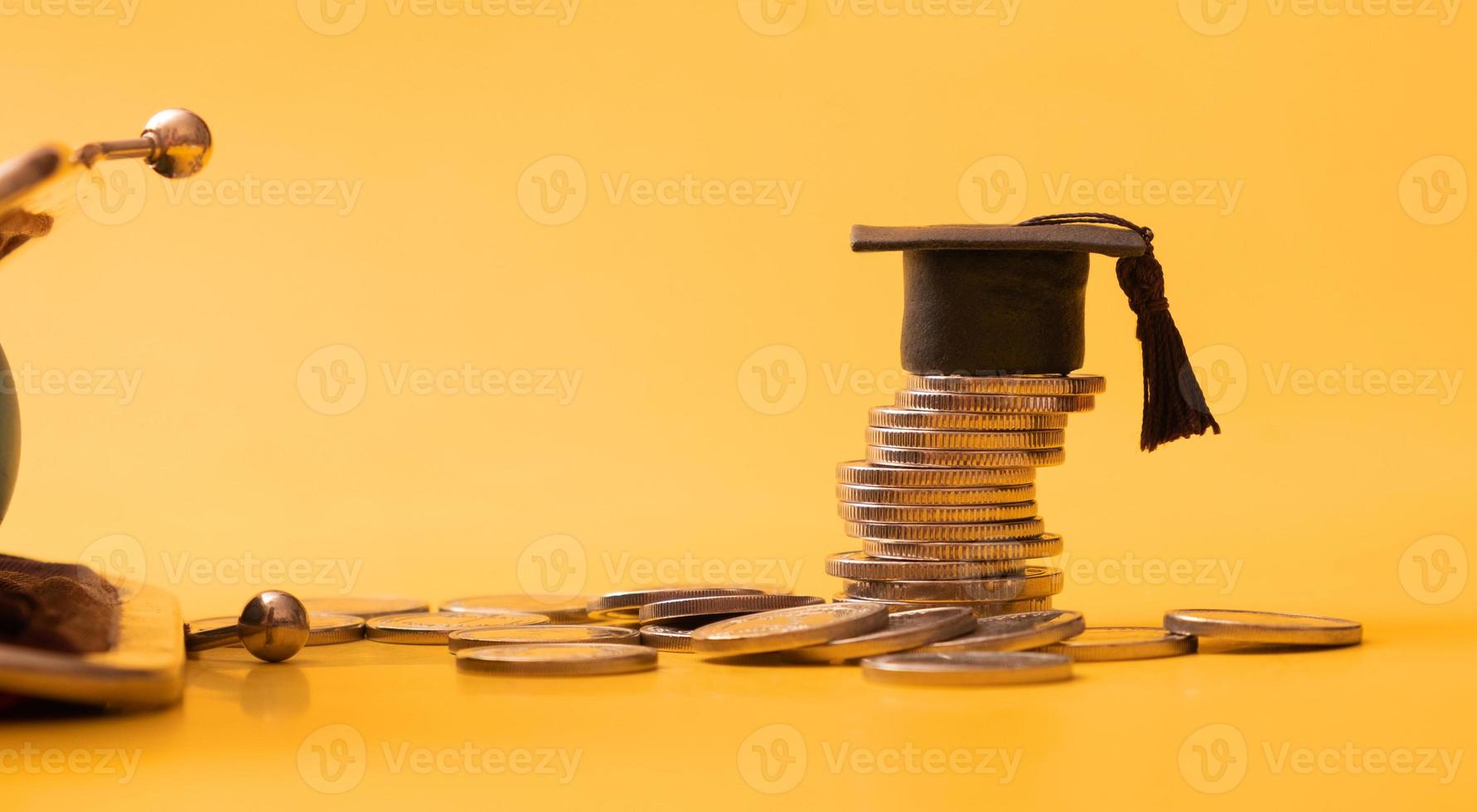 Graduated cap with coins and wallet fragment on orange background. Financial literacy concept photo