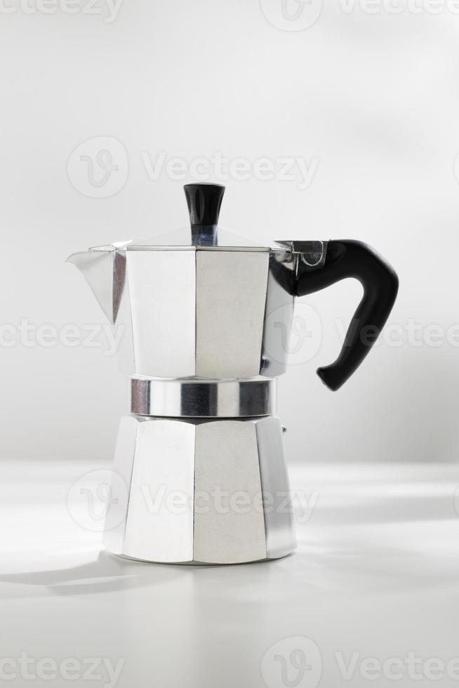 Moka pot espresso machine on a white table. photo