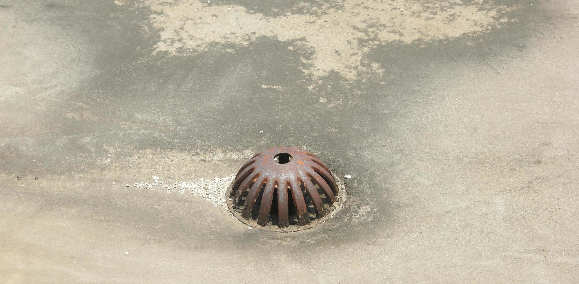 Old rustic water drain with metal iron material on roof top isolated on concrete flooring. photo