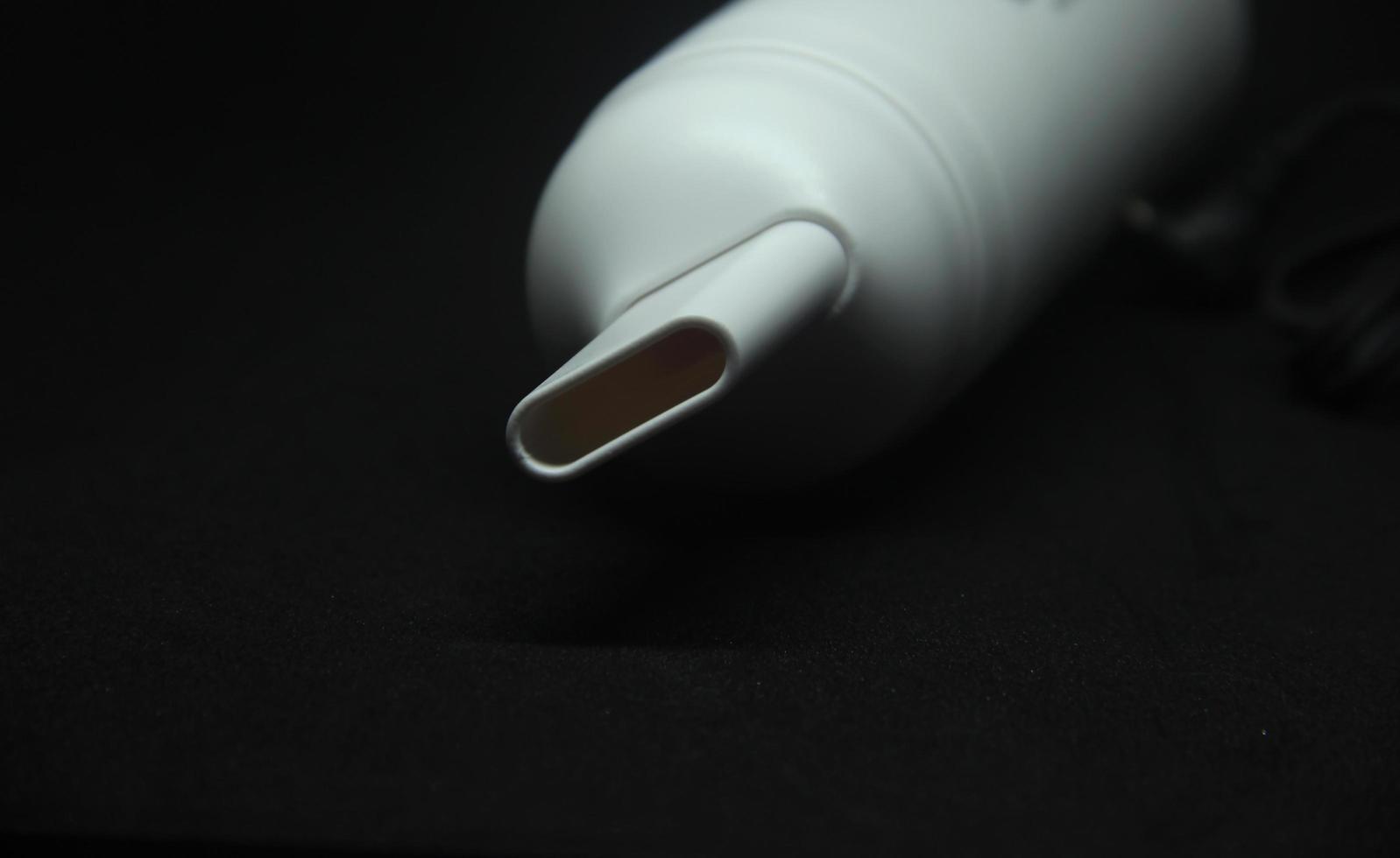 Small hand held desk white vacuum for cleaning crumbs on the table or keyboard close up vacuum hole isolated photo on dark black background.