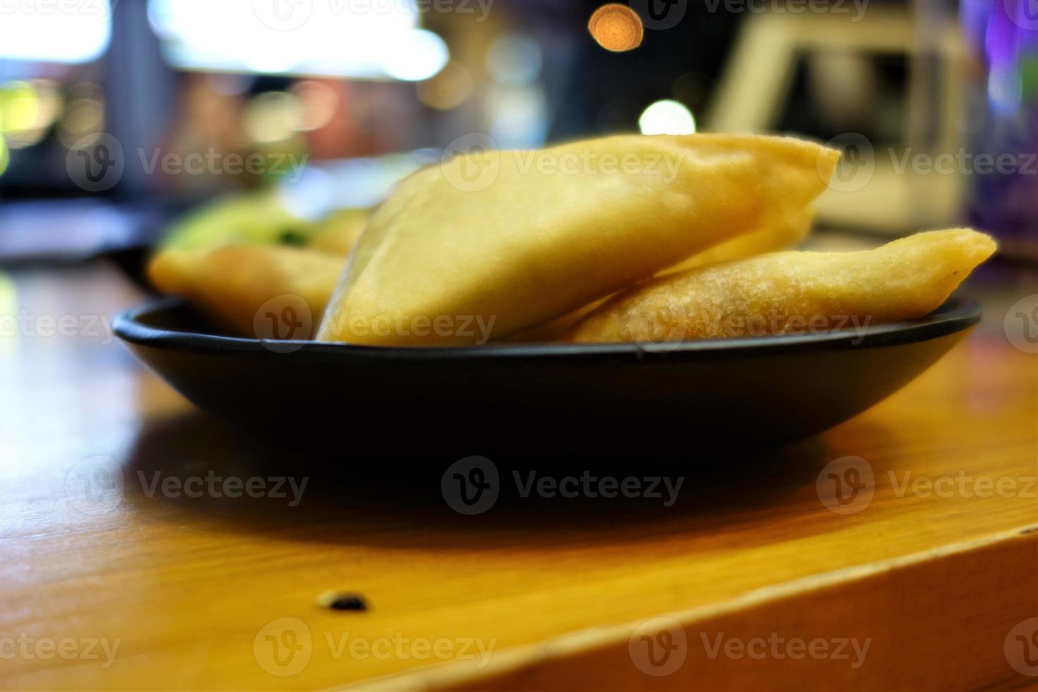 Samosas on a black plate as a close up photo