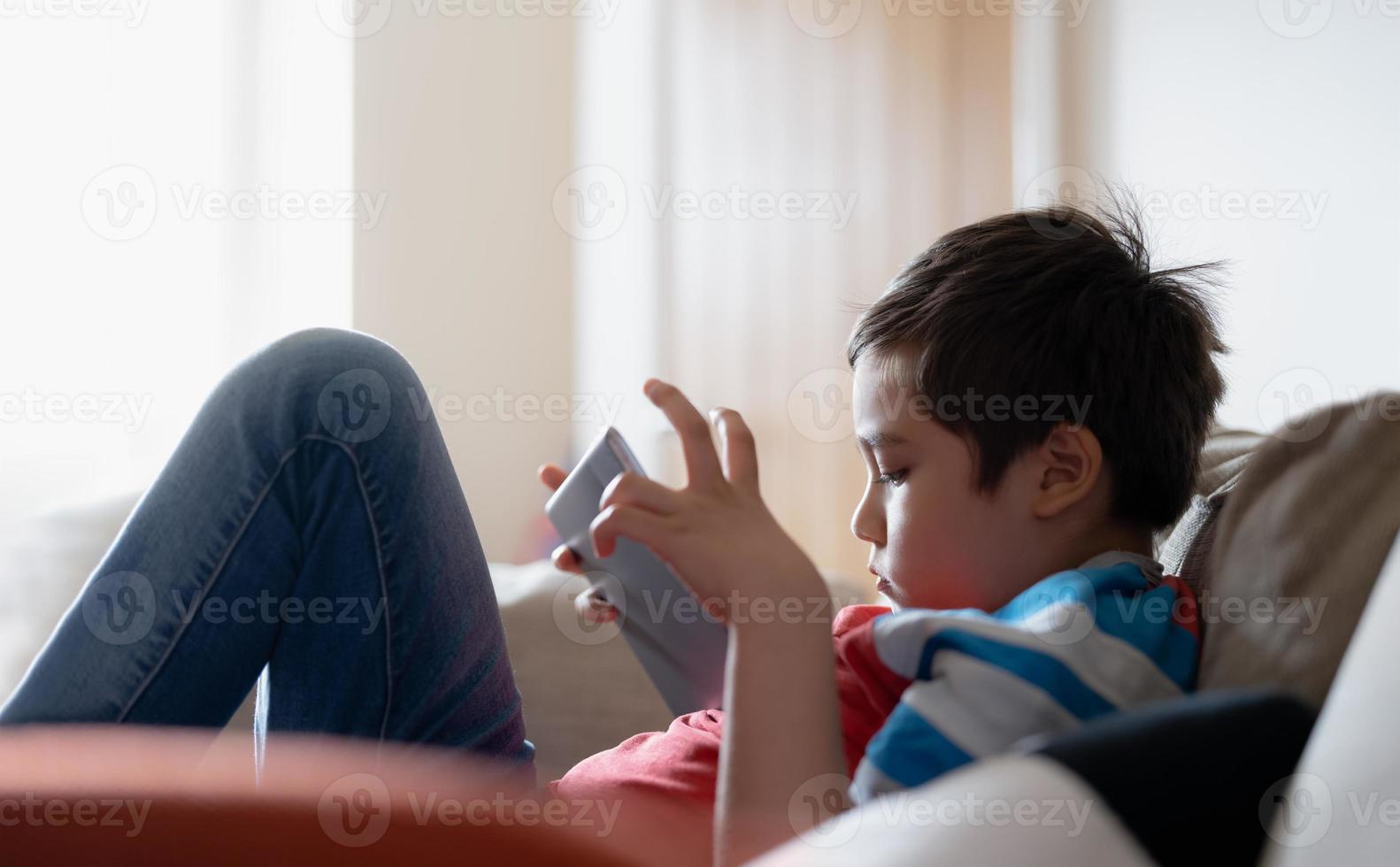 Education concept,School kid using tablet readying story from internet,Boy studying online learning at home,High key protrait Child holding digital pad using wifi playing game,Back to School photo