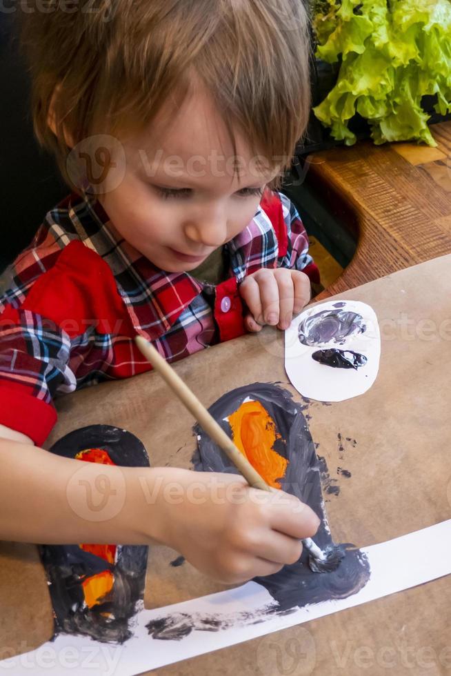 boy drawing the ears of a handmade Easter bunny made of cardboard. Preparation for the celebration of the Easter holiday. photo