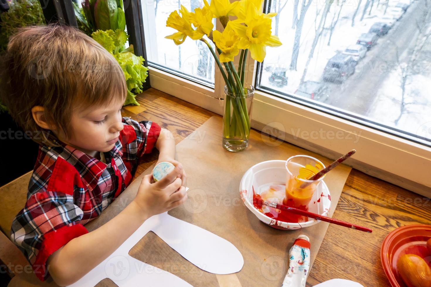 boy drawing the ears of a handmade Easter bunny made of cardboard. Preparation for the celebration of the Easter holiday. photo