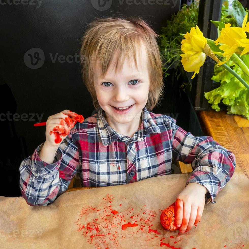 el niño preparando para Pascua de Resurrección. pintar huevos. rojo pintar huevo. foto