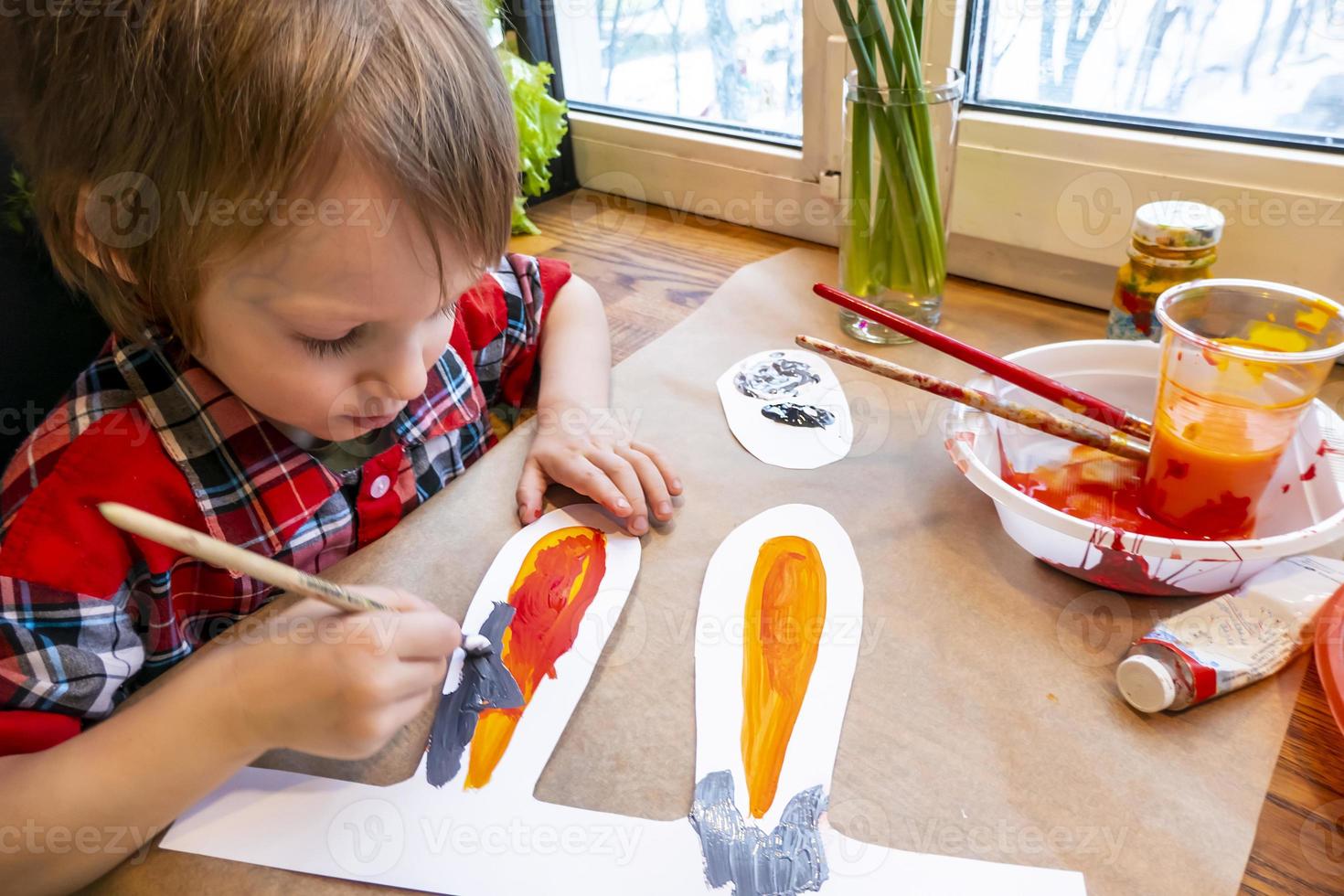 boy drawing the ears of a handmade Easter bunny made of cardboard. Preparation for the celebration of the Easter holiday. photo