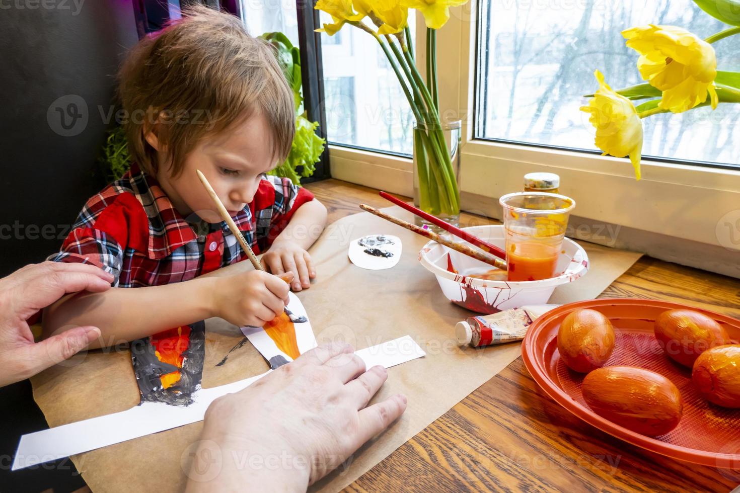 boy drawing the ears of a handmade Easter bunny made of cardboard. Preparation for the celebration of the Easter holiday. photo