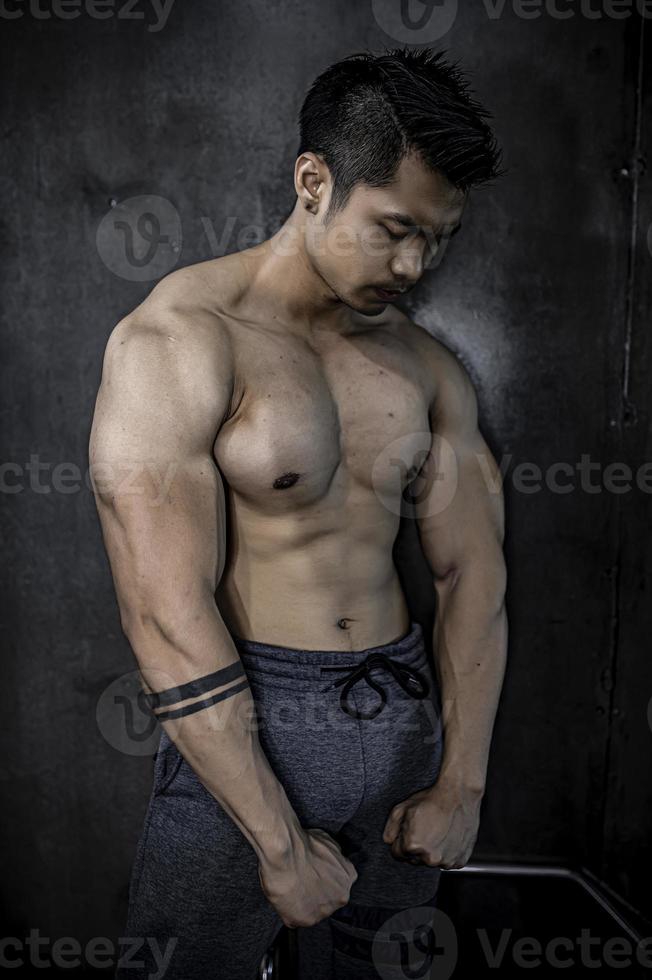 retrato de hombre asiático con gran músculo en el gimnasio, gente de tailandia, entrenamiento para una buena salud, entrenamiento de peso corporal, fitness en el concepto de gimnasio foto