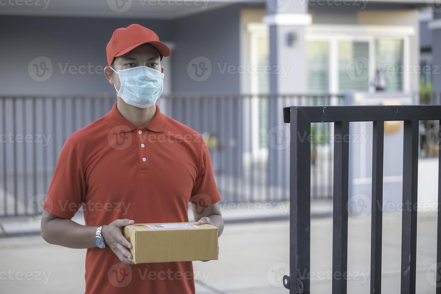 Asian Delivery  man wear protective mask in red uniform,Online food and product delivery concept,New normal in covid-19 photo