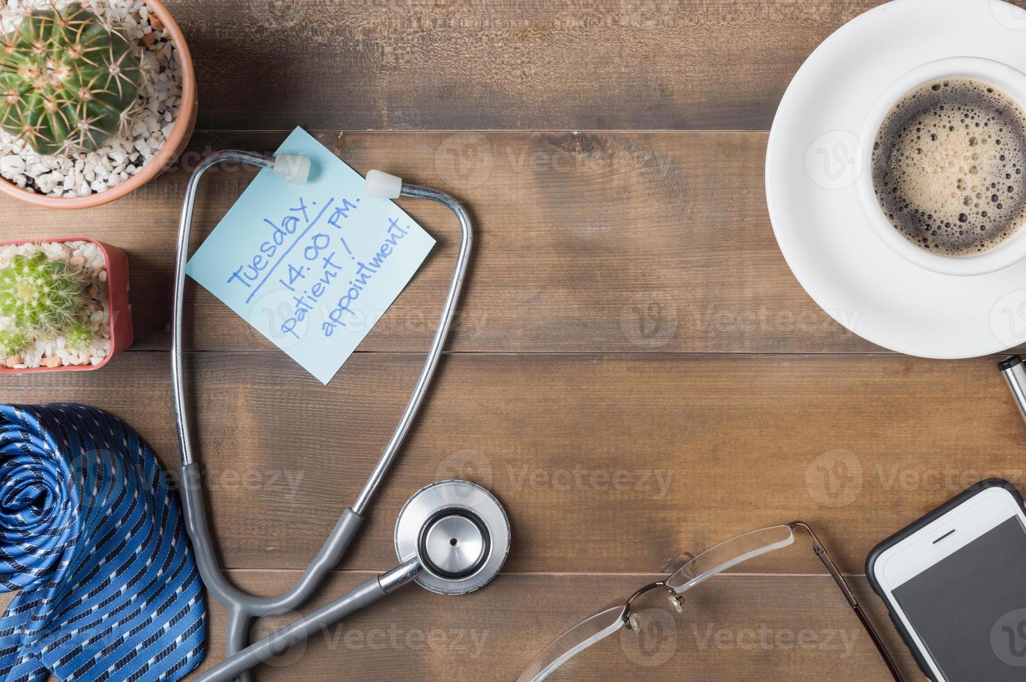 paper note patient appointment on wood blackboard wiith Stethoscope, necktie, smartphone, coffee glasses and cactus on wood background photo