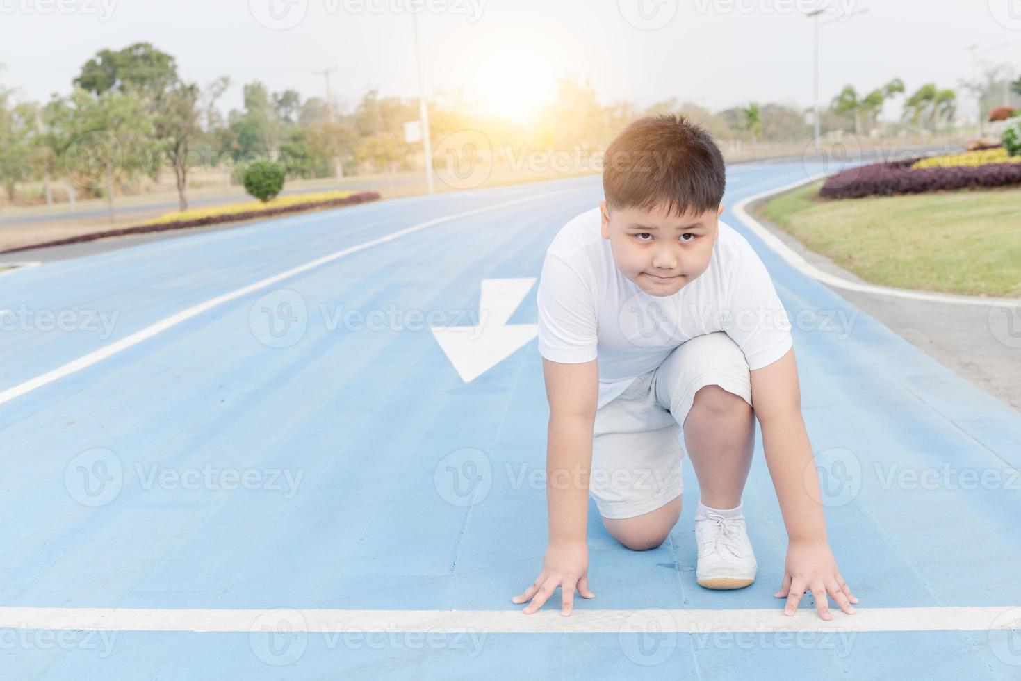 fit and confident fat boy in starting position ready for running photo