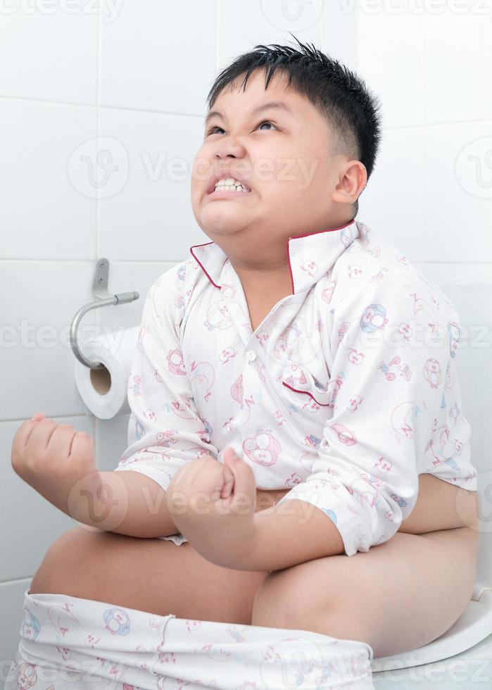 Fat boy sitting on the toilet. photo