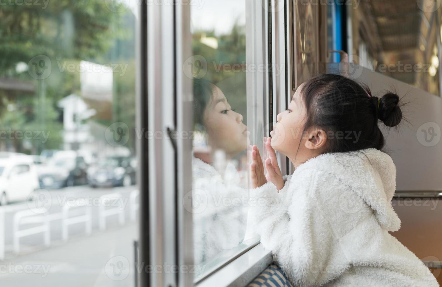 pequeño niña mirando mediante ventana. ella viajes en un tren. foto