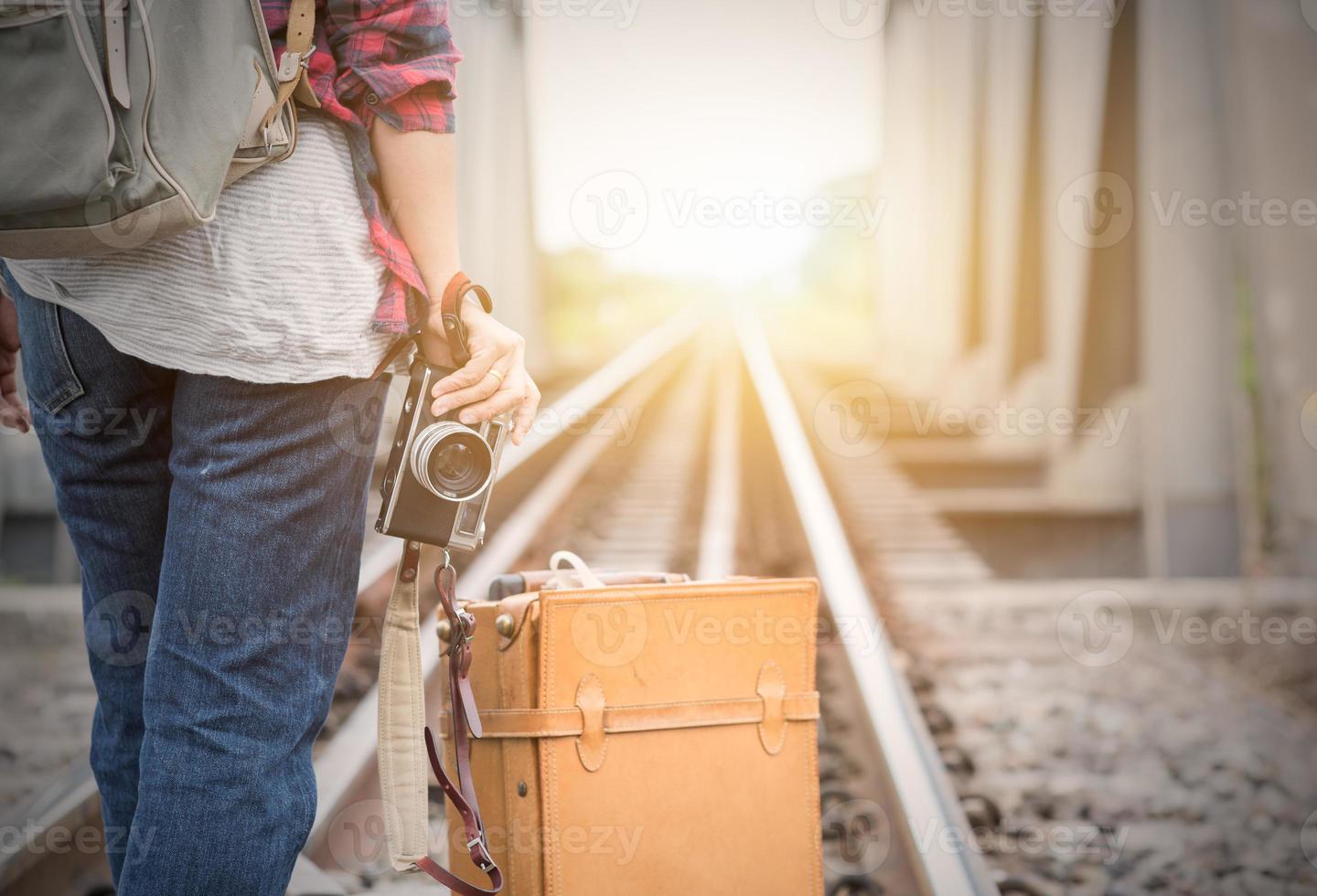 Traveler holding vintage camera in hand on railway background photo