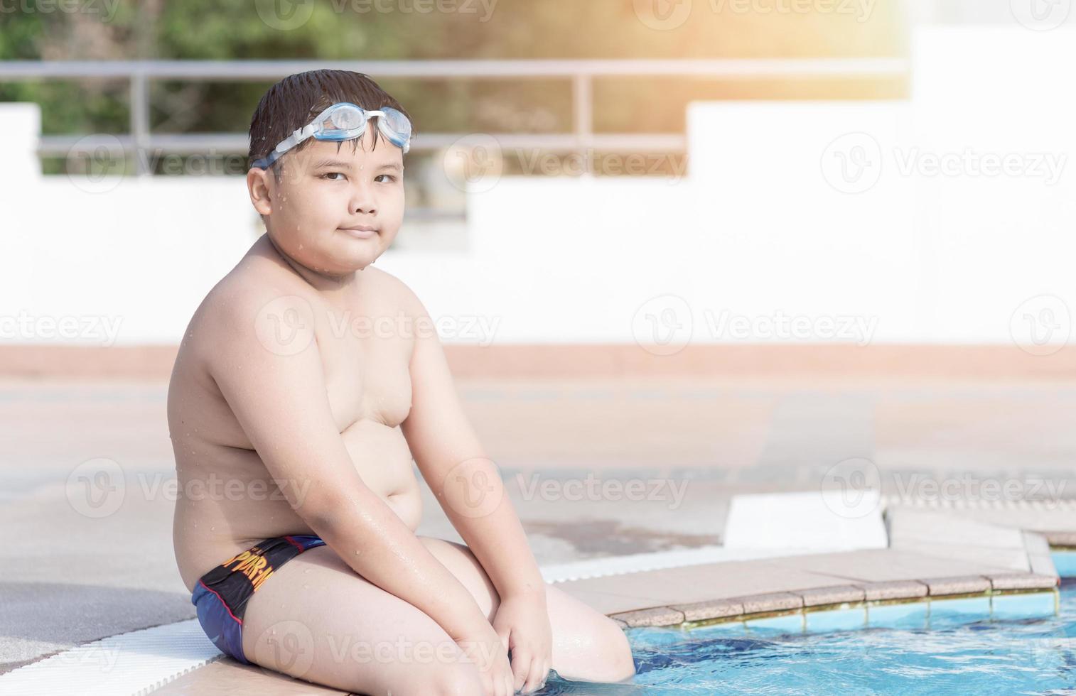 obeso grasa chico sentado en nadando piscina foto