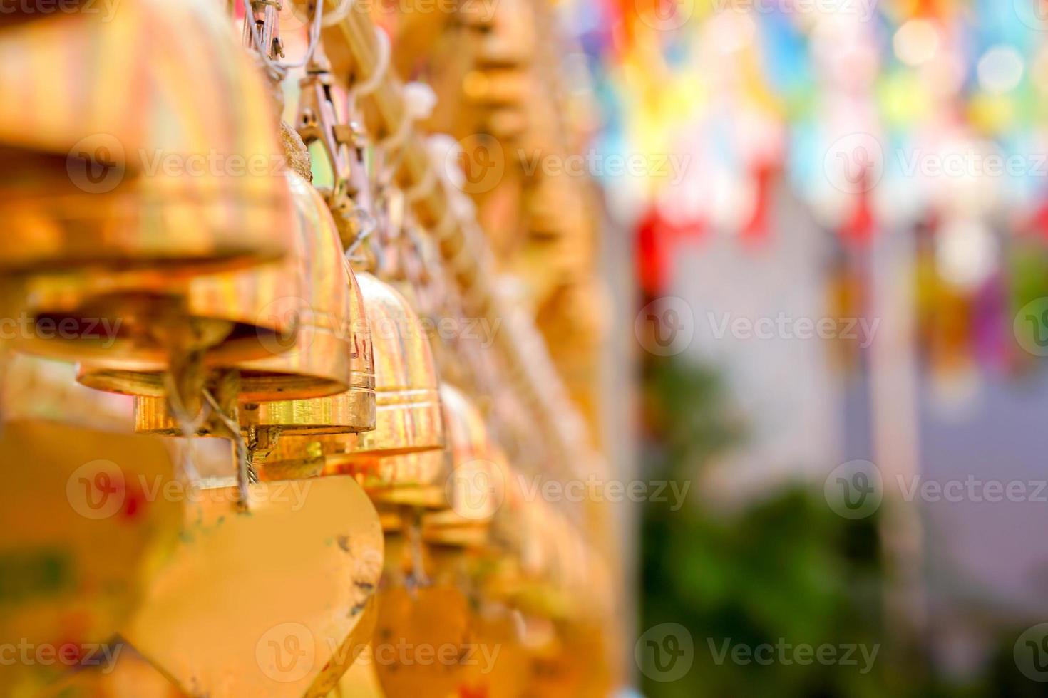 Closeup and perspective view group of small golden bells hang in Thai temple on blurry background. photo