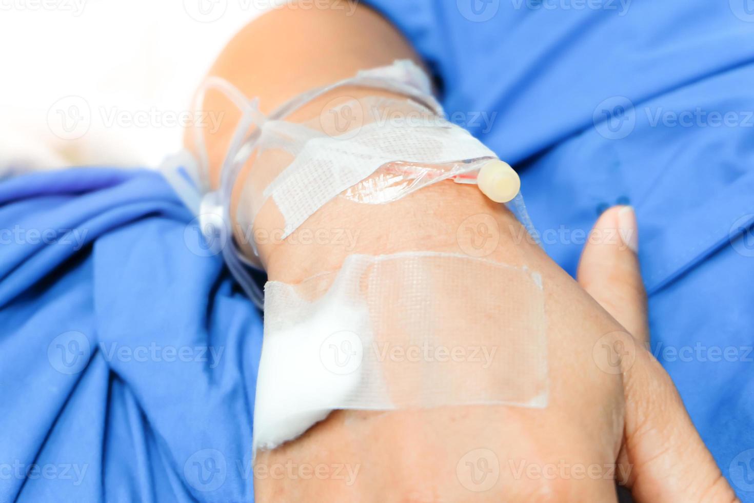 Close up of saline drip in patient's hand . Asian woman with  hospital admission. photo