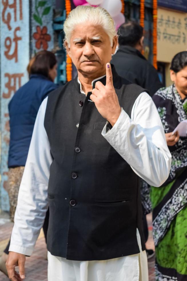 New Delhi, India - December 04 2022 - Unidentified people showing their ink-marked fingers after casting votes in front of polling booth of east Delhi area for MCD local body Elections 2022 photo