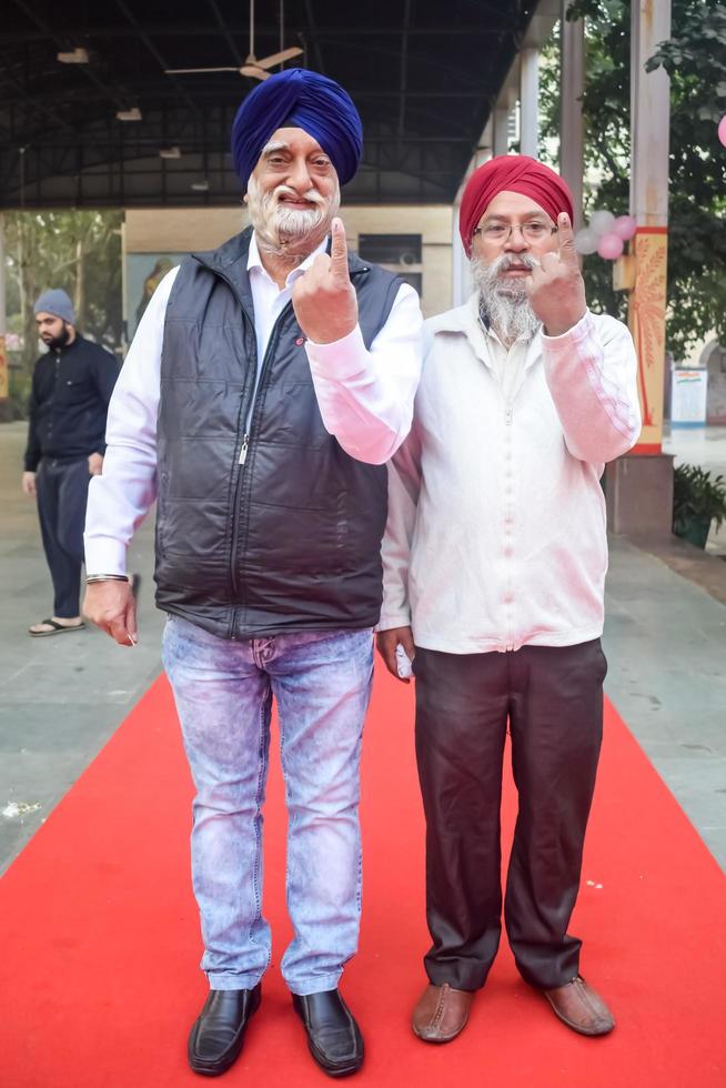 New Delhi, India - December 04 2022 - Unidentified people showing their ink-marked fingers after casting votes in front of polling booth of east Delhi area for MCD local body Elections 2022 photo