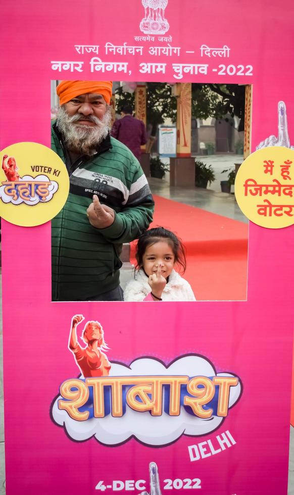 New Delhi, India - December 04 2022 - Unidentified people showing their ink-marked fingers after casting votes in front of polling booth of east Delhi area for MCD local body Elections 2022 photo