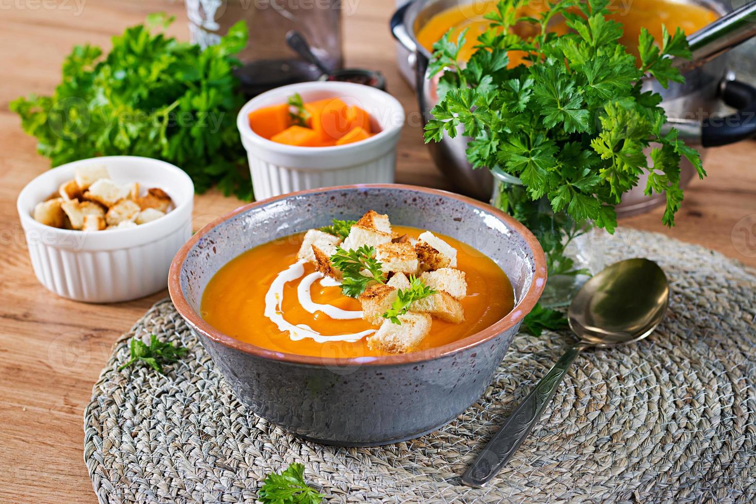 Pumpkin soup in a bowl served with parsley and croutons. Vegan soup. Thanksgiving day food. Halloween meal. photo