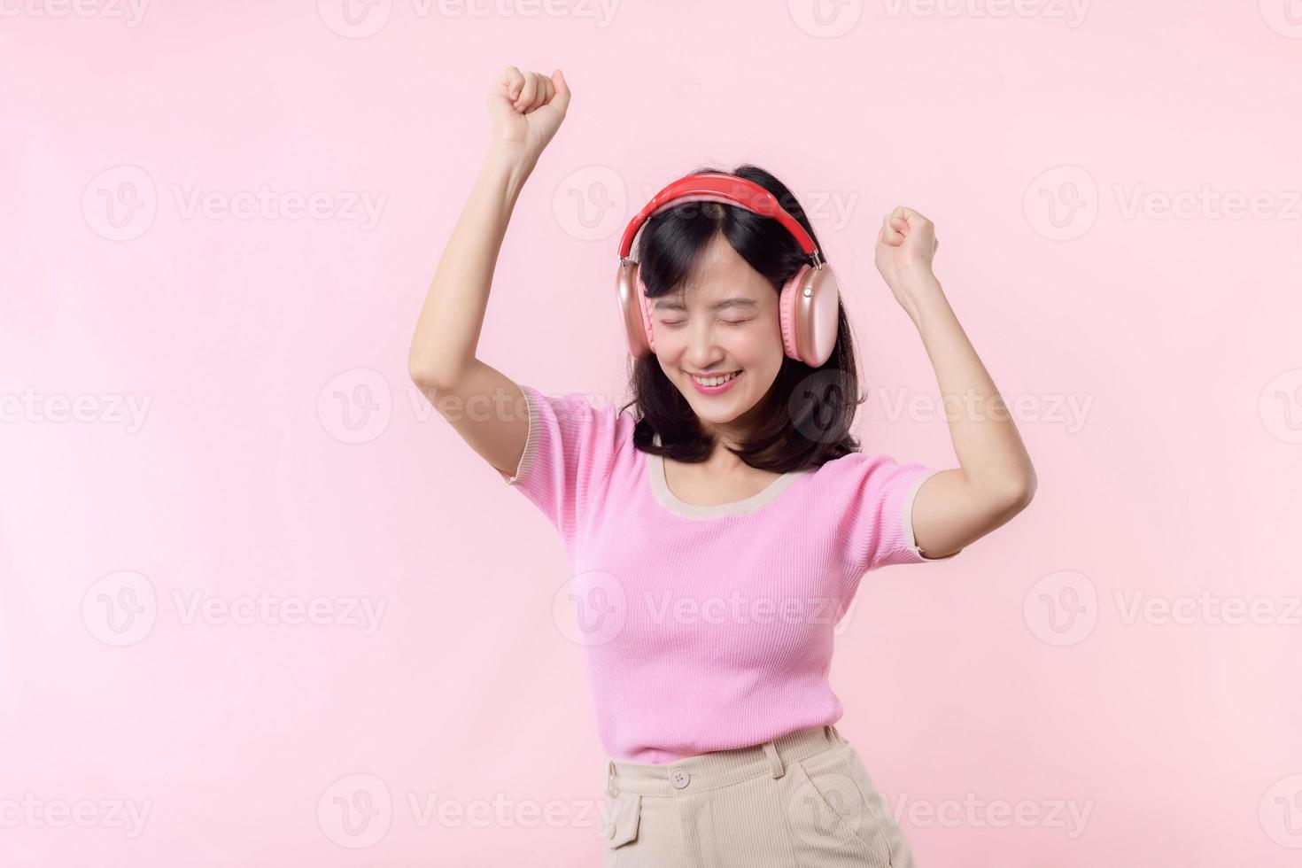 sonrisa bonito modelo persona escucha música canción y disfrutar danza con inalámbrico auricular en línea audio radio sonido. positivo divertido salido alegre juventud hembra mujer canta en rosado aislado antecedentes estudio foto