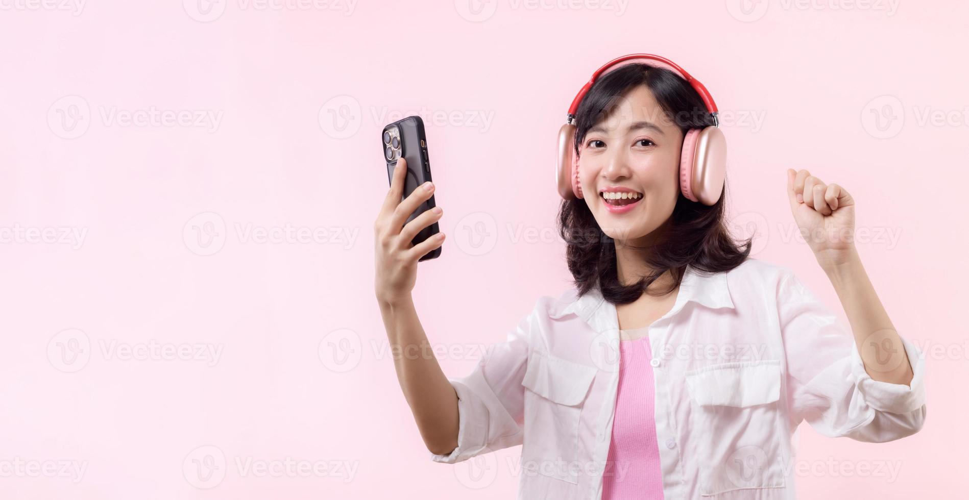 People emotions, lifestyle leisure and beauty concept. Carefree good-looking asian woman dancing relaxed with smartphone, listening music in wireless headphones photo