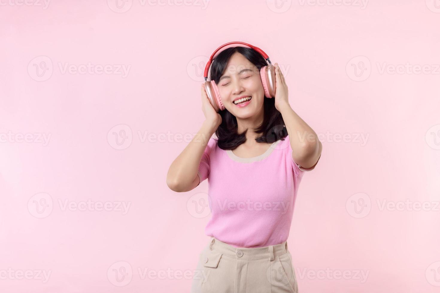 sonrisa bonito modelo persona escucha música canción y disfrutar danza con inalámbrico auricular en línea audio radio sonido. positivo divertido salido alegre juventud hembra mujer canta en rosado aislado antecedentes estudio foto