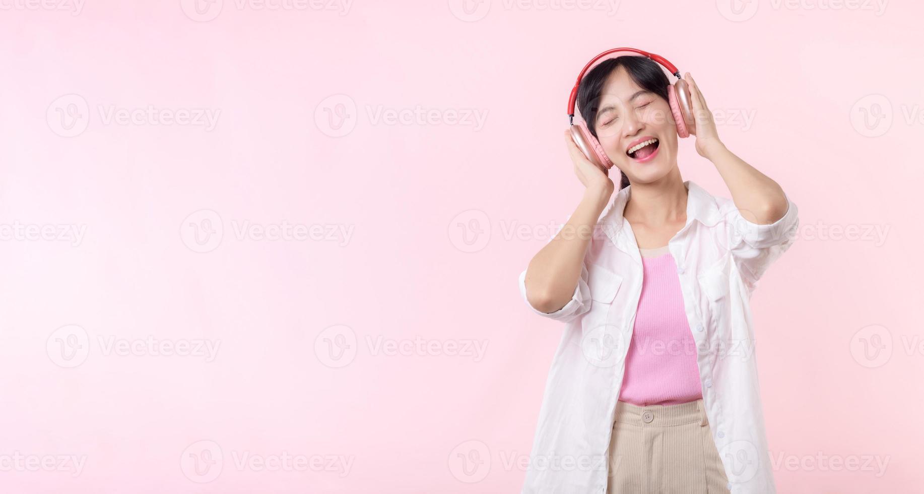 sonrisa bonito modelo persona escucha música canción y disfrutar danza con inalámbrico auricular en línea audio radio sonido. positivo divertido salido alegre juventud hembra mujer canta en rosado aislado antecedentes estudio foto
