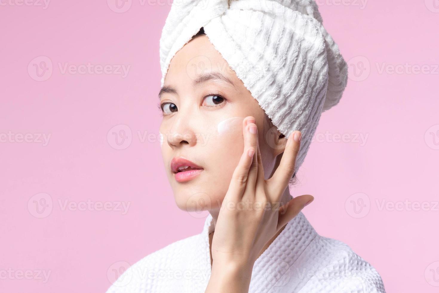 Young asian woman applying facial skincare face cream, cosmetic moisturiser on healthy natural skin make up face. Portrait glowing smile girl person model with care beauty product, spa, cosmetology. photo