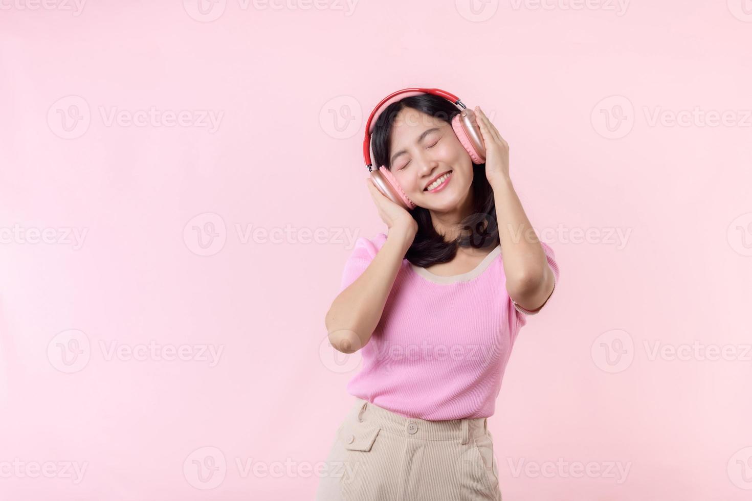 Smile pretty model person listen music song and enjoy dance with wireless headphone online audio radio sound. Positive fun exited joyful youth female woman sing on pink isolated background studio photo