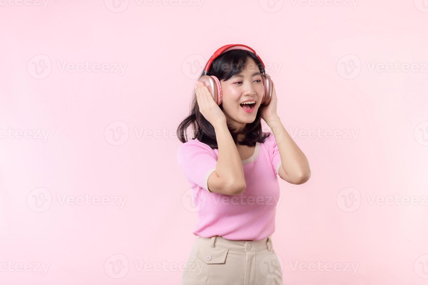 sonrisa bonito modelo persona escucha música canción y disfrutar danza con inalámbrico auricular en línea audio radio sonido. positivo divertido salido alegre juventud hembra mujer canta en rosado aislado antecedentes estudio foto