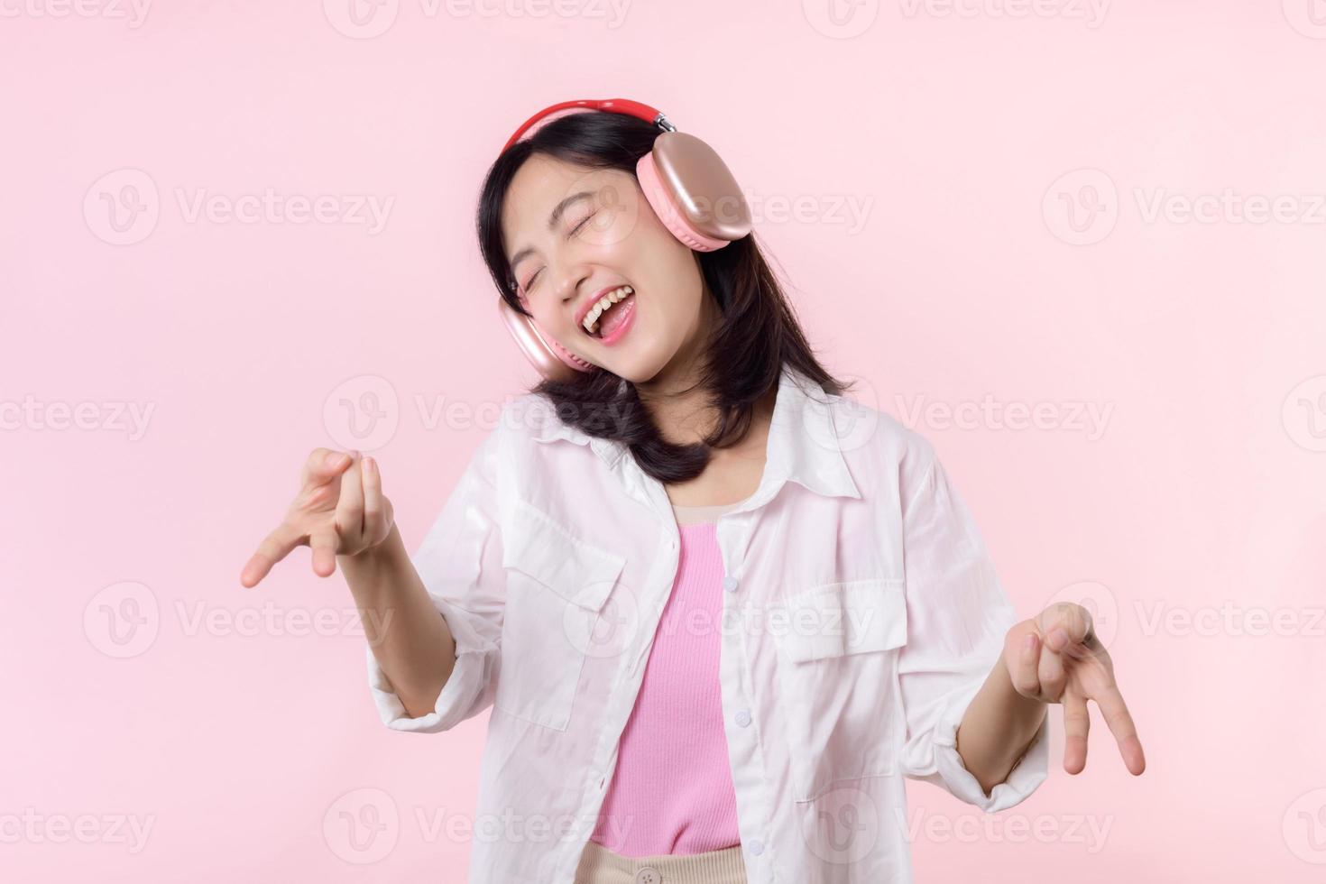 Smile pretty model person posing Y2K, listen music song and enjoy dance with headphone online audio radio sound. Positive fun exited joyful youth female woman sing on pink isolated background studio photo