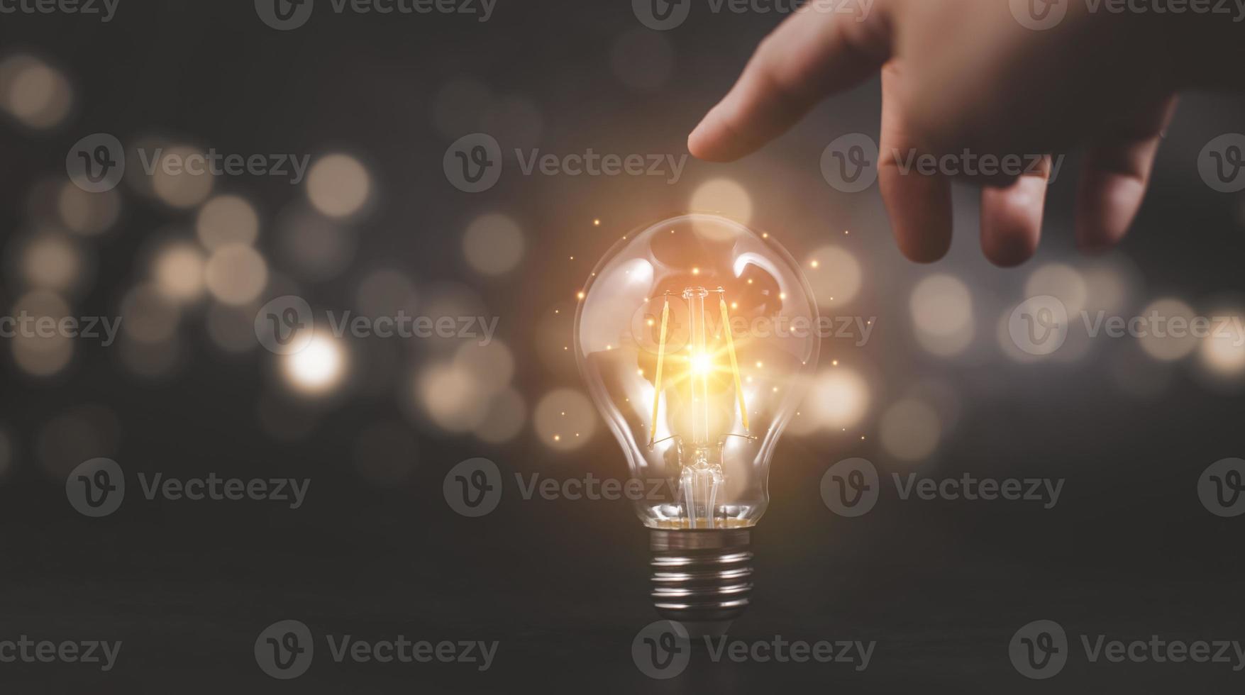 Thinking and creative concept, Hand touch light bulb style bokeh vintage dark background,Concept The idea of reading books, knowledge, and searching for new ideas. photo