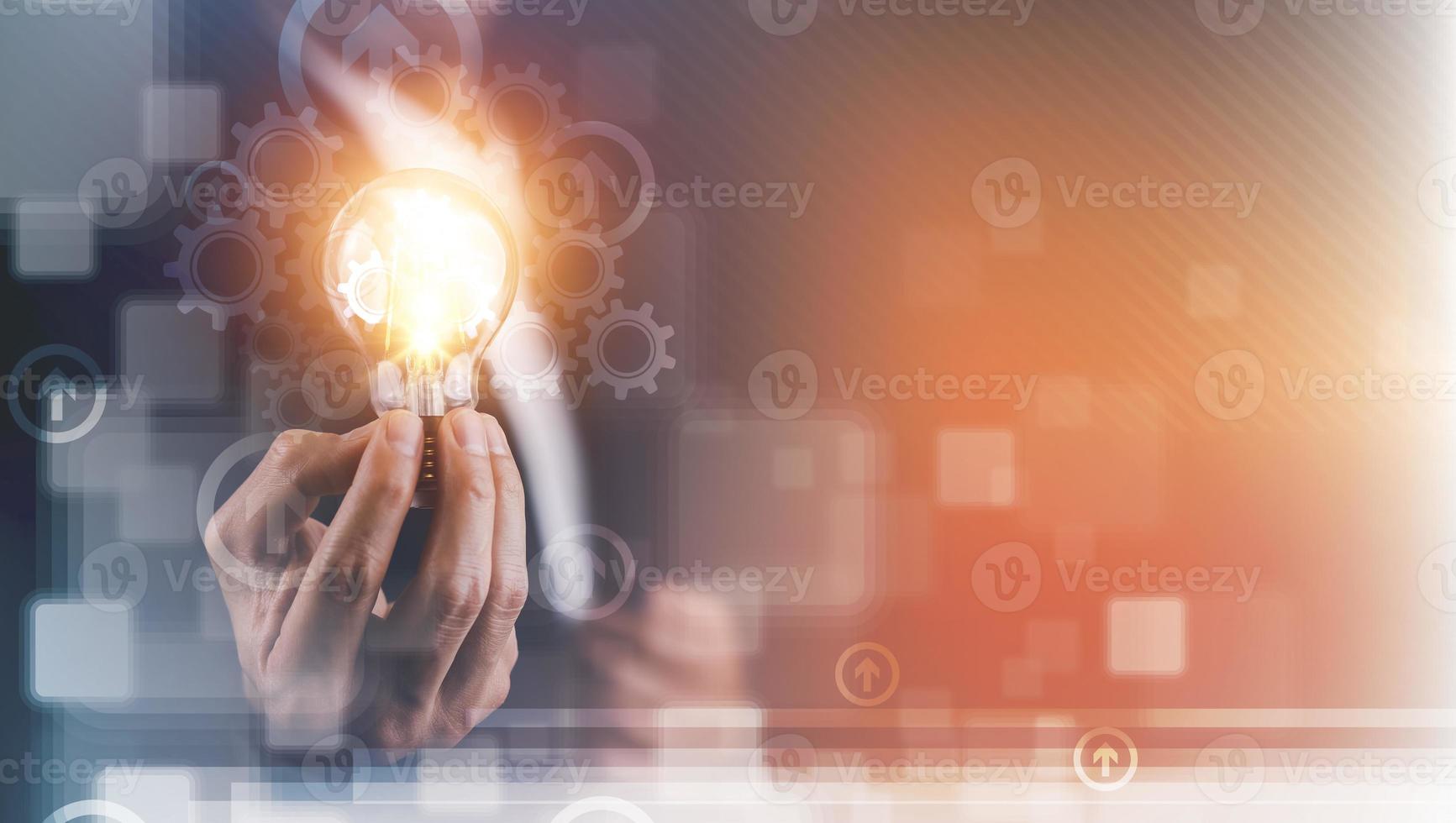 Businessman hand holding light bulb with icons and working on the desk, Creativity and innovation are keys to success.Concept of new idea and innovation with energy and power , working at home, photo