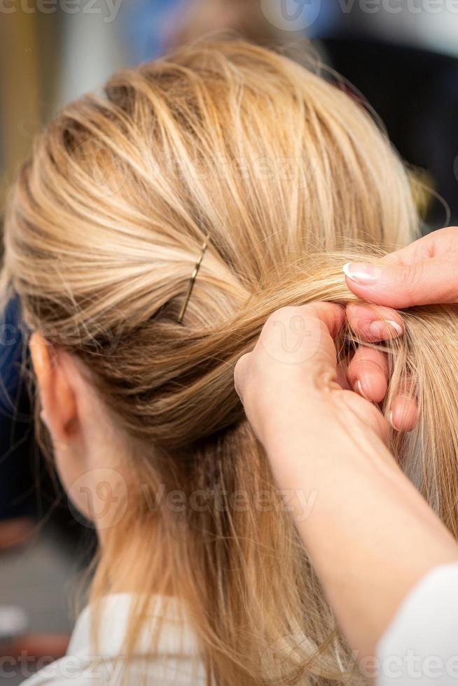 Hairdresser's hands braiding client's hair photo
